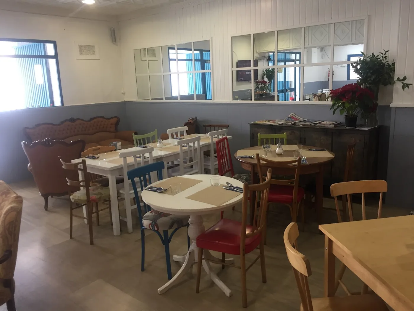 Interior real de Cafe Bar La Ilusión: sillas pintadas de rojo amapola, azul cielo y verde manzana, sofá isabelino terracota y carpintería blanca de estilo shabby-chic.